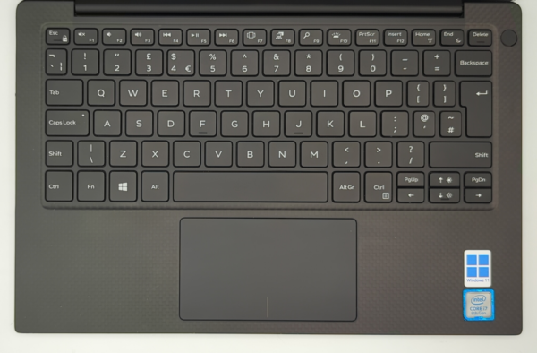 Laptop keyboard with trackpad, Windows 11, and Intel Core i7 sticker, viewed from above.
