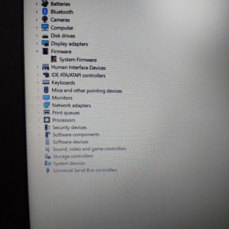 Device Manager window showing hardware components like audio, Bluetooth, cameras, and system firmware on a desktop.
