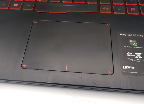 Close-up of a laptop touchpad and keyboard, featuring ASUS TUF Gaming branding and specifications label.