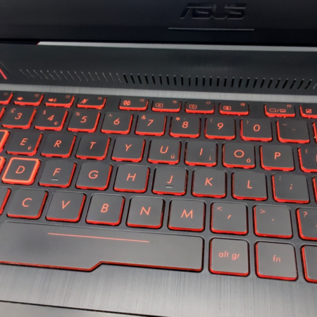 Backlit keyboard with red accents on a laptop, showcasing sleek design and illuminated keys for gaming or typing.