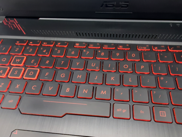 Backlit keyboard with red accents on a laptop, showcasing sleek design and illuminated keys for gaming or typing.
