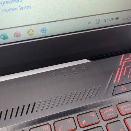 Close-up of a gaming laptop with illuminated red keyboard and open screen displaying software agreement text.