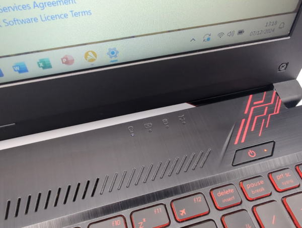 Close-up of a gaming laptop with illuminated red keyboard and open screen displaying software agreement text.