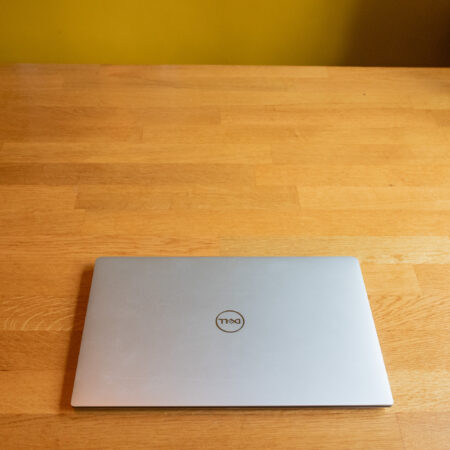 Closed silver laptop on a wooden table, viewed from above in a minimalist setting.
