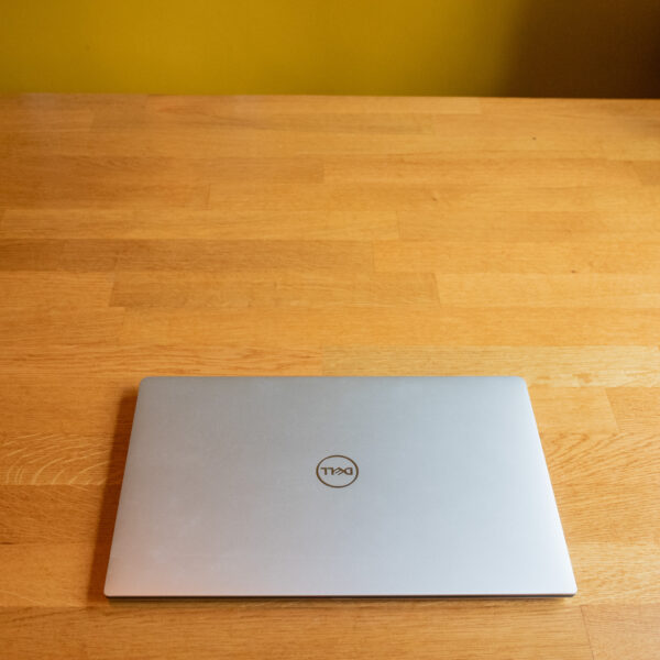 Closed silver laptop on a wooden table, viewed from above in a minimalist setting.