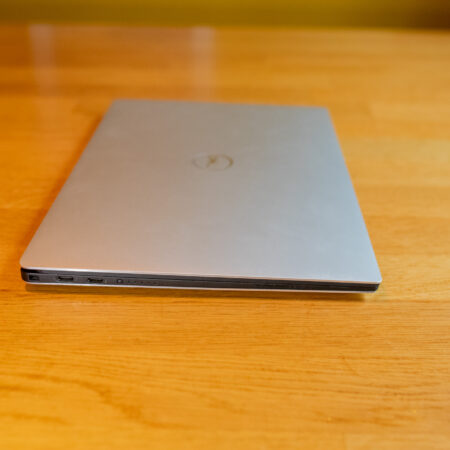Closed silver laptop on wooden table, showcasing slim profile and modern design.