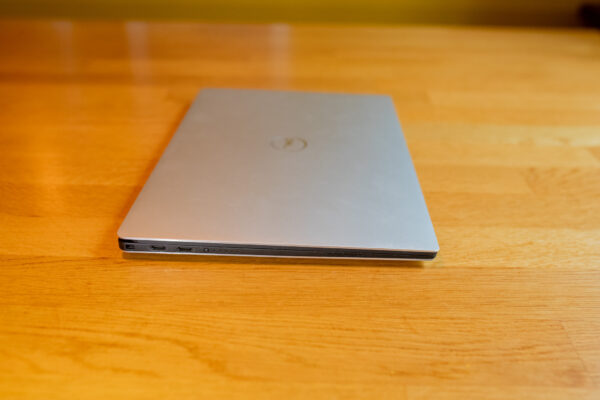 Closed silver laptop on wooden table, showcasing slim profile and modern design.
