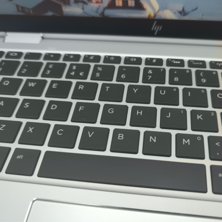 Close-up of a laptop keyboard with black keys and a silver frame, featuring a QWERTY layout.