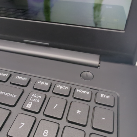 Close-up of a laptop keyboard and screen hinge, featuring navigation keys and power button.