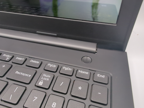 Close-up of a laptop keyboard and screen hinge, featuring navigation keys and power button.