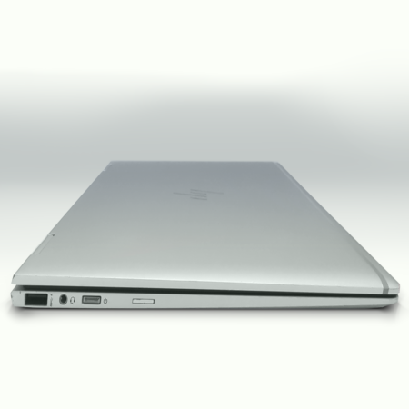 Sleek silver laptop closed on white background, ports visible, showcasing modern and slim design.