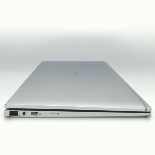Sleek silver laptop closed on white background, ports visible, showcasing modern and slim design.