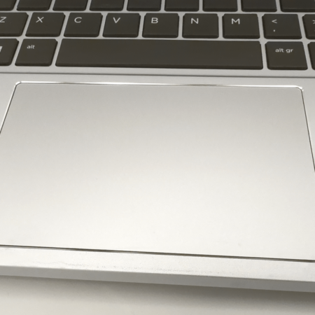 Close-up of a laptop touchpad and keyboard, featuring a silver design with a sleek and modern aesthetic.
