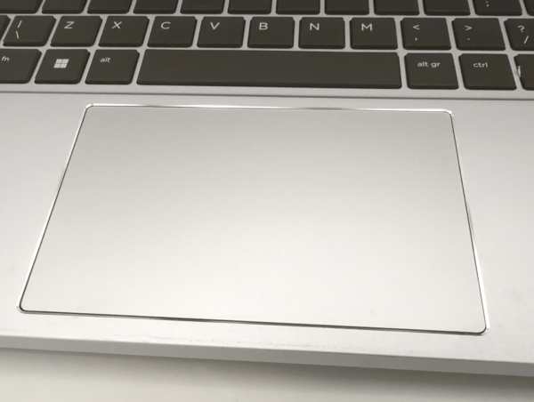 Close-up of a laptop touchpad and keyboard, featuring a silver design with a sleek and modern aesthetic.
