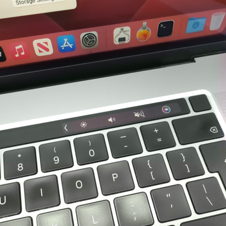 Close-up of a MacBook Pro keyboard with Touch Bar, showcasing app icons and controls on a laptop screen.