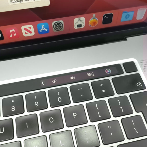 Close-up of a MacBook Pro keyboard with Touch Bar, showcasing app icons and controls on a laptop screen.