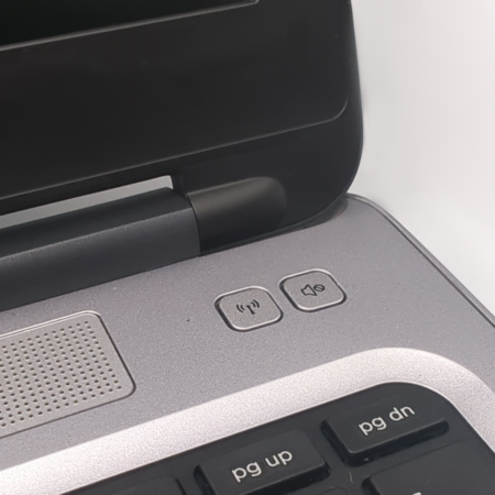 Close-up of laptop hinge and keyboard, featuring volume controls and speaker section.