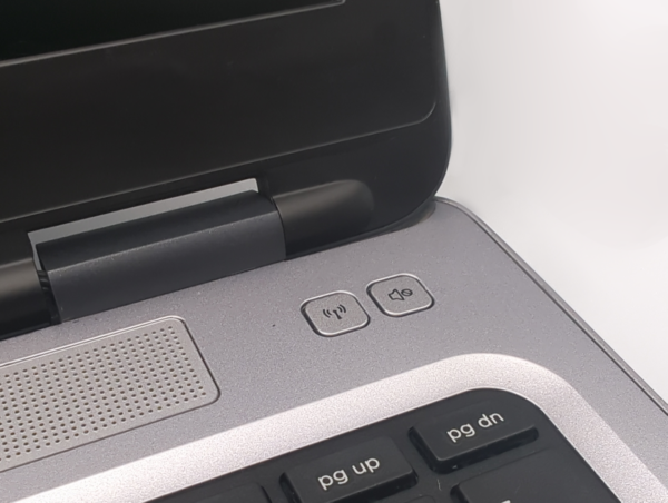 Close-up of laptop hinge and keyboard, featuring volume controls and speaker section.