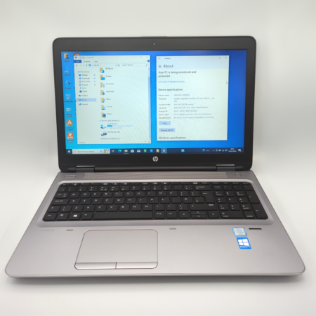 Silver HP laptop displaying Windows screen with device specifications in a bright setting.