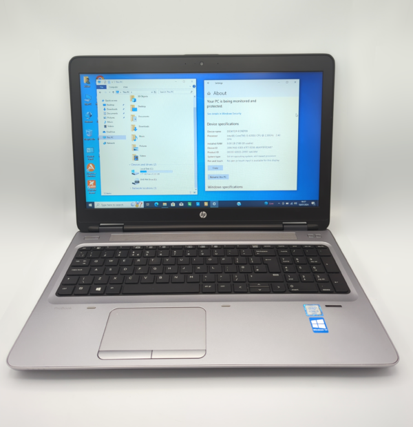 Silver HP laptop displaying Windows screen with device specifications in a bright setting.