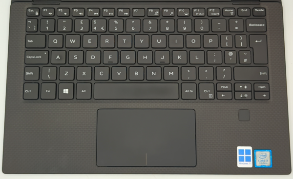 Black laptop keyboard and touchpad with Windows 11 and Intel Core i7 stickers on the palm rest.