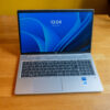 Silver laptop on wooden desk with a blue screen display showing the time as 13:04, featuring Windows and Intel Core stickers.