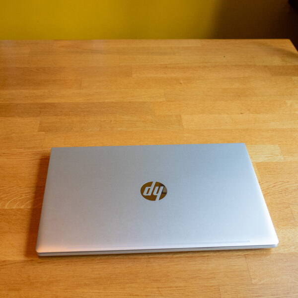 Closed silver laptop on a wooden table, showcasing its sleek design and minimalist logo.