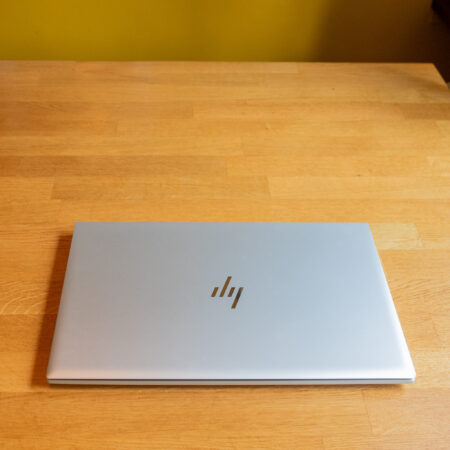 Closed silver laptop on a wooden table, showcasing a sleek and minimalist design.