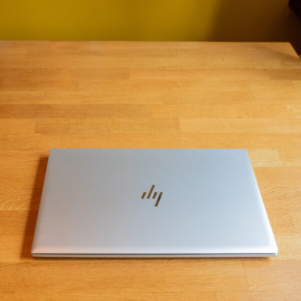 Closed silver laptop on a wooden table, showcasing a sleek and minimalist design.