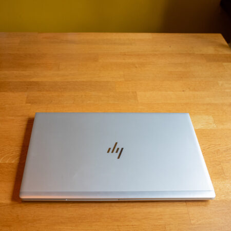 Closed silver laptop on a wooden desk, viewed from above, showcasing its sleek design and metallic finish.