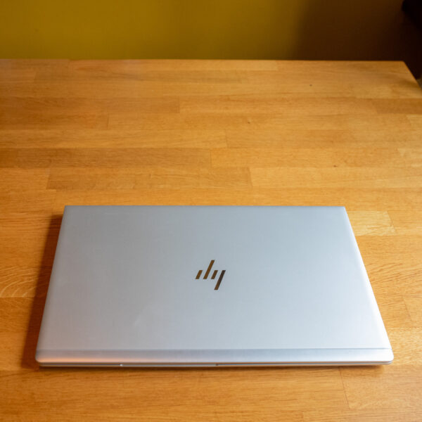 Closed silver laptop on a wooden desk, viewed from above, showcasing its sleek design and metallic finish.