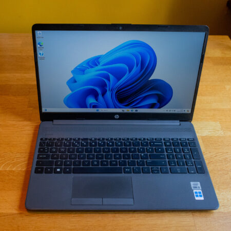 HP laptop displaying Windows 11 on a wooden desk.