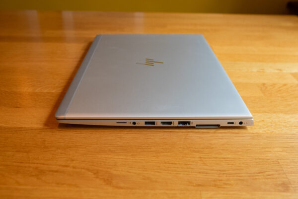 Silver laptop with multiple ports on a wooden desk.