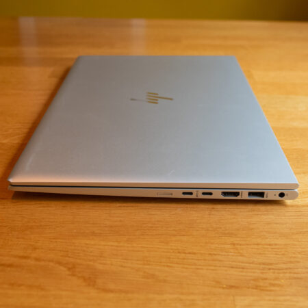 Sleek silver laptop with closed lid on wooden table, showcasing various ports and minimalist design.