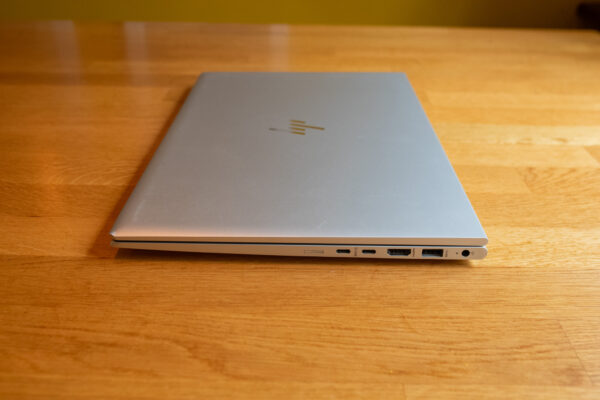 Sleek silver laptop with closed lid on wooden table, showcasing various ports and minimalist design.