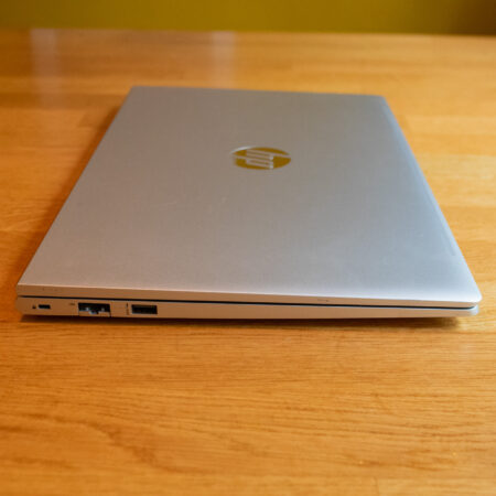 Closed silver laptop on a wooden surface, featuring visible ports on the left side.