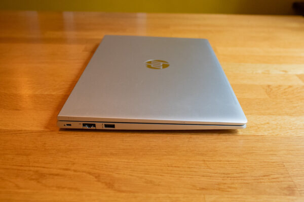 Closed silver laptop on a wooden surface, featuring visible ports on the left side.