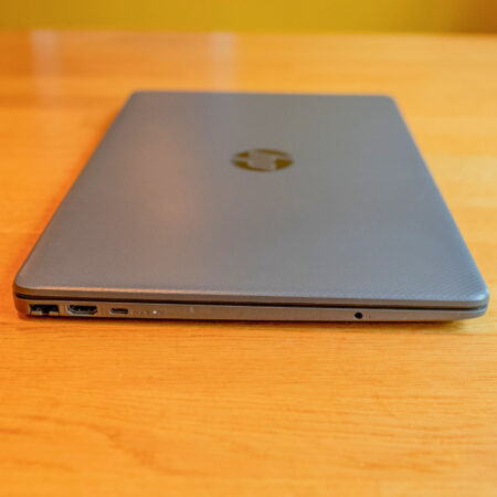 Silver laptop on wooden desk, showcasing side ports for connectivity.