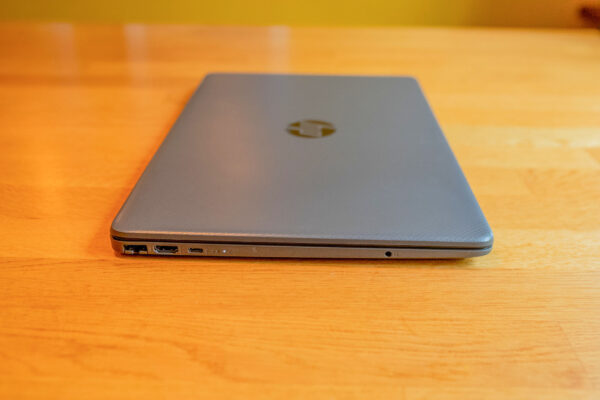 Silver laptop on wooden desk, showcasing side ports for connectivity.