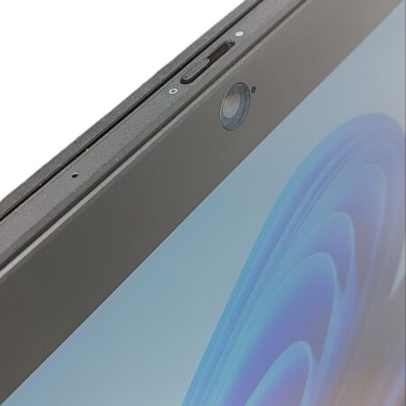 Close-up of a laptop webcam with privacy cover, screen displaying blue abstract pattern.