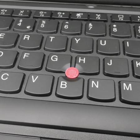Close-up of a laptop keyboard with a red trackpoint.