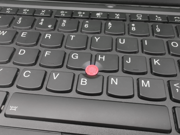 Close-up of a laptop keyboard with a red trackpoint.