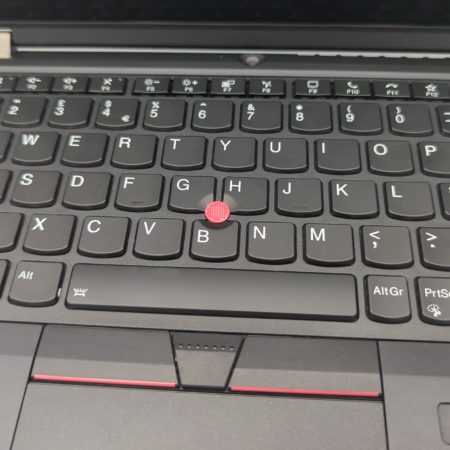 Laptop keyboard with red pointing stick, highlighting unique ergonomic design feature.