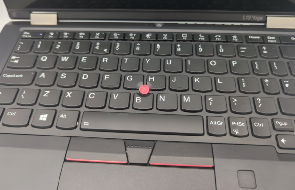 Laptop keyboard with red pointing stick, highlighting unique ergonomic design feature.