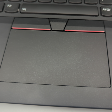 Close-up of a laptop touchpad with black and red accents, highlighting the keyboard's lower section.