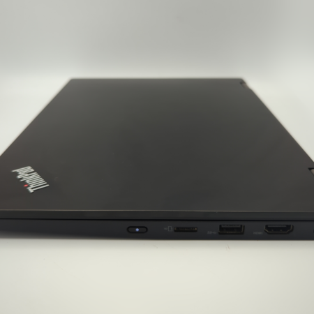 Closed black laptop with visible brand logo, showing multiple port connections on the side, on a white surface.