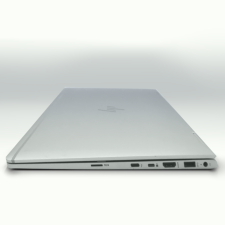Closed silver laptop with various ports and sleek design on a light background.