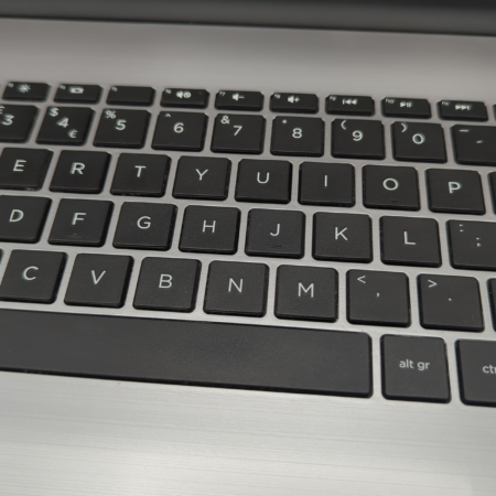 Close-up of a black keyboard on a silver laptop, highlighting QWERTY layout and function keys.