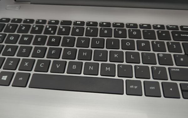 Close-up of a black keyboard on a silver laptop, highlighting QWERTY layout and function keys.