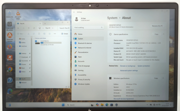 Laptop displaying Windows 11 system information and local disk space with applications visible on the desktop.